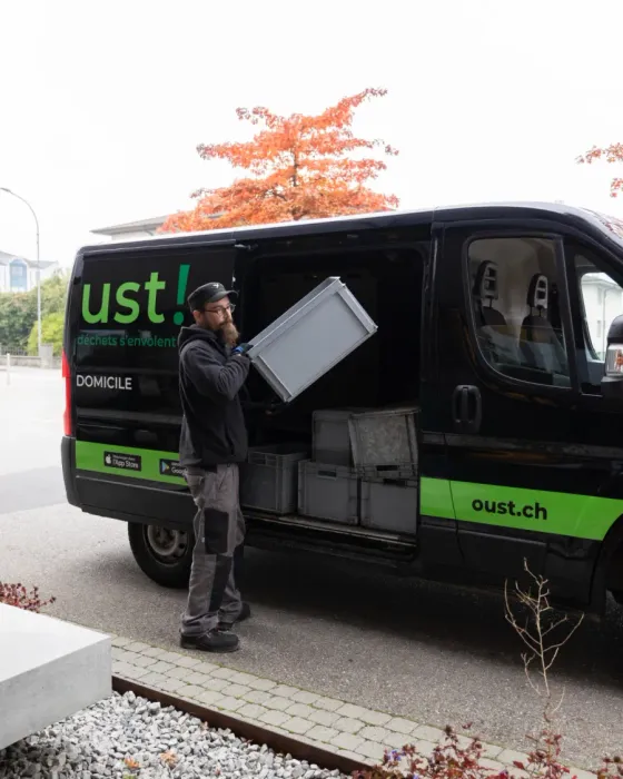 Un chauffeur Oust! charge des caisses dans un véhicule