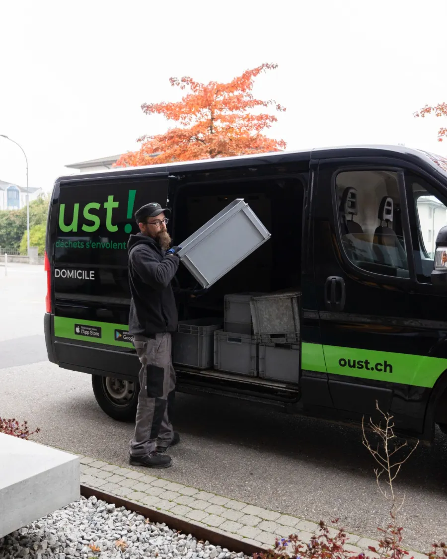 Un chauffeur Oust! charge des caisses dans un véhicule